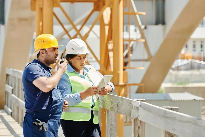 A site supervisor and colleague reviewing plans on a construction project — Avaib