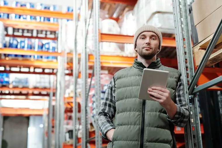A worker using a tablet for inventory management in a warehouse — Avaib