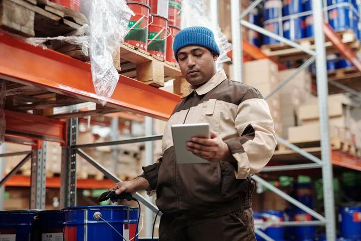A logistics worker scanning packages with a tablet in a warehouse — Avaib