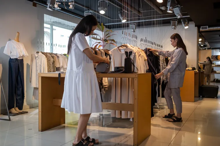 Two shoppers browsing clothing racks in a boutique store — Avaib