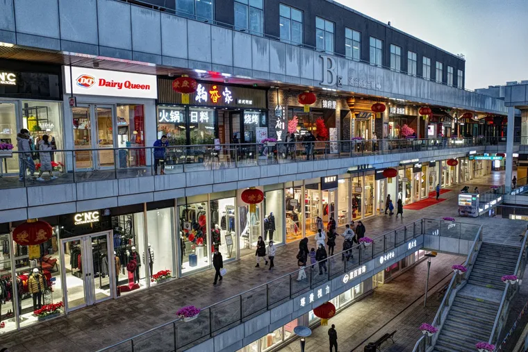Shoppers walking through a shopping mall past storefronts — Avaib