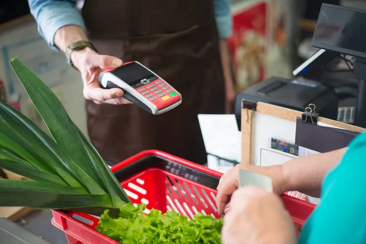 A shopper paying at a retail counter while a cashier serves them — Avaib