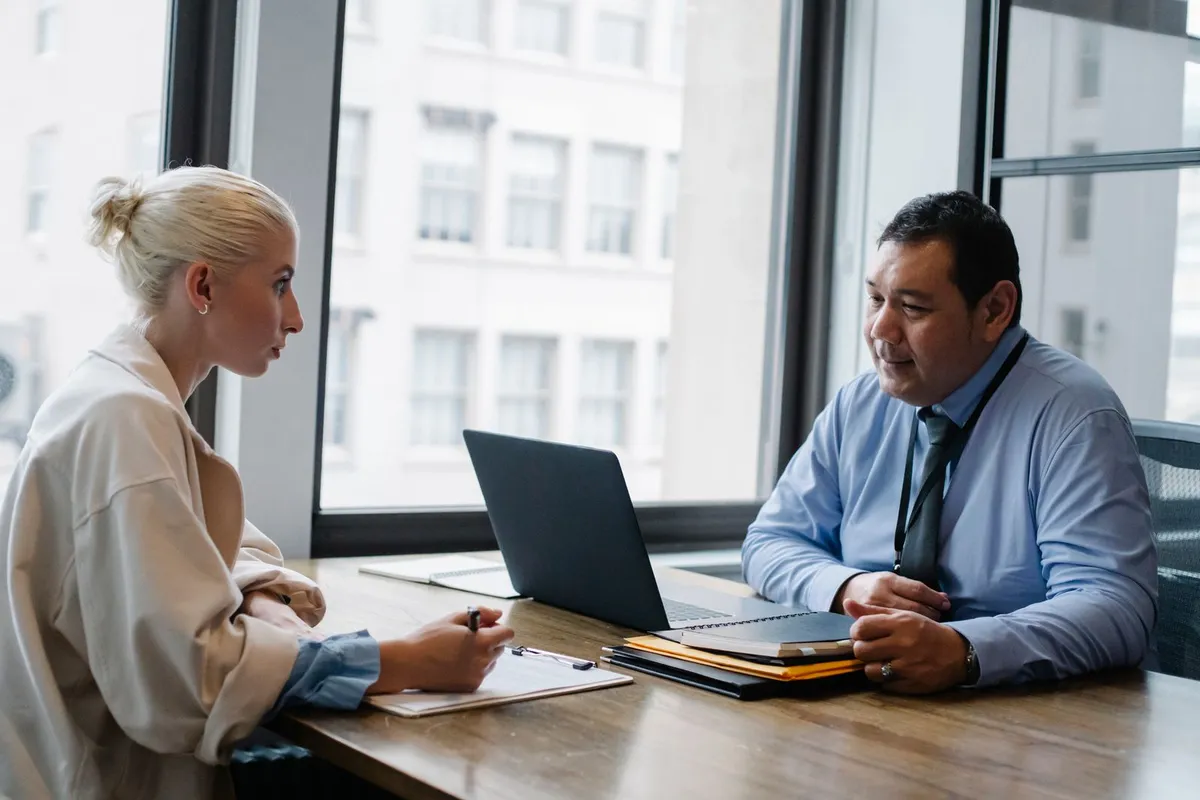 A recruiter interviewing a candidate across a desk in an office